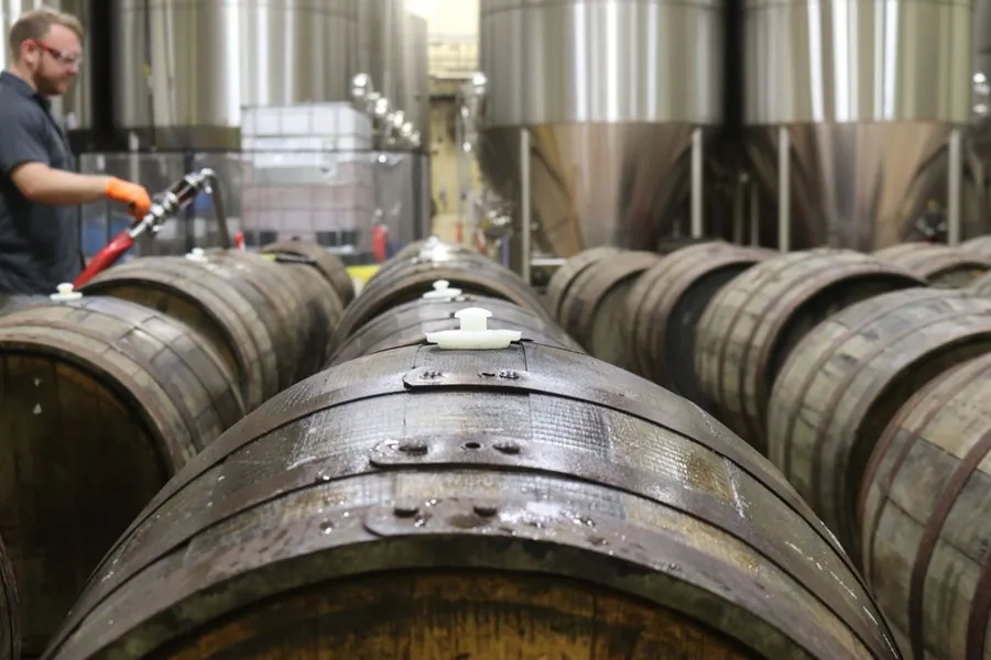 Rows of wooden cask ale barrels being racked at a brewery